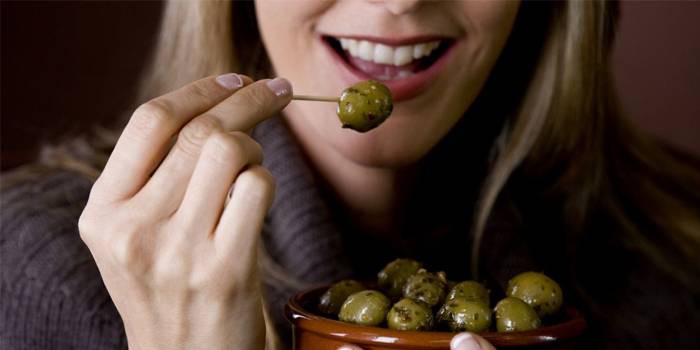 Девушка ест оливки