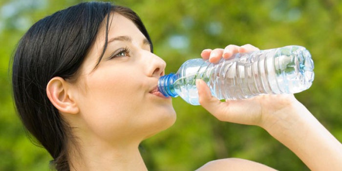 Девушка пьет воду для выведения соли из организма