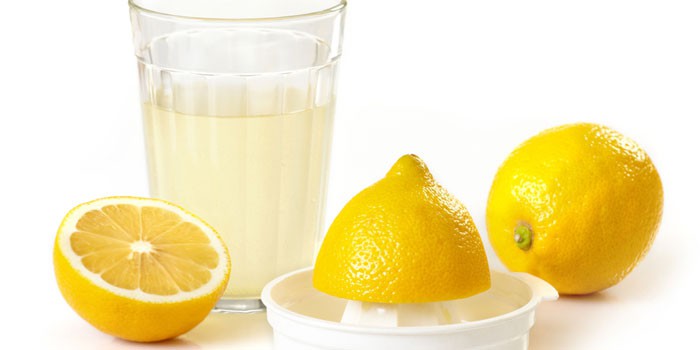 Лимонный сок в стакане и лимоны