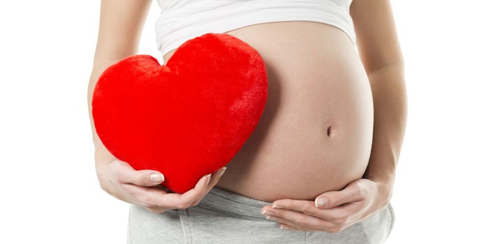 Беременная девушка с подушкой в форме сердца